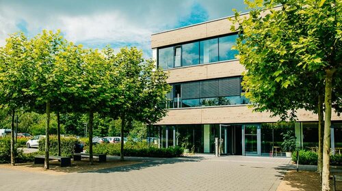 Das Hauptgebäude der Wirtschaftsakademie hinter Bäumen